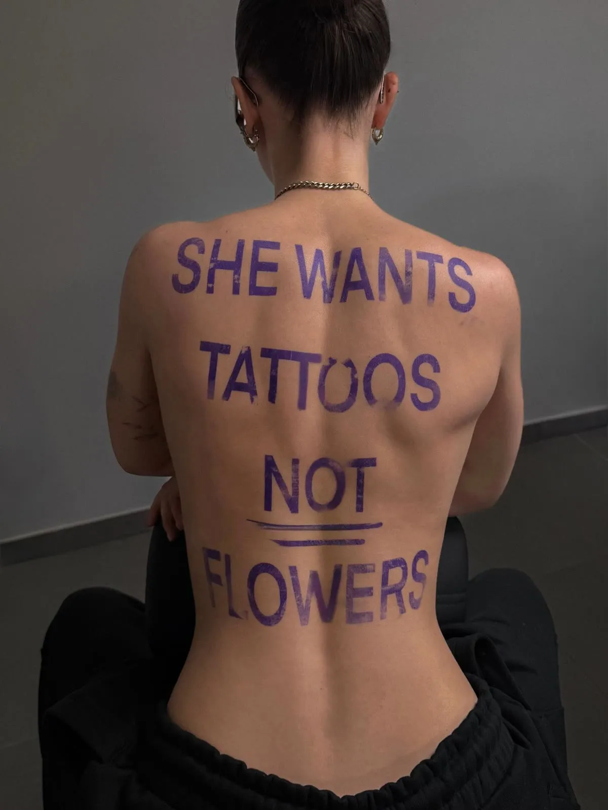 Large script across a back reading she wants tattoos, not flowers.