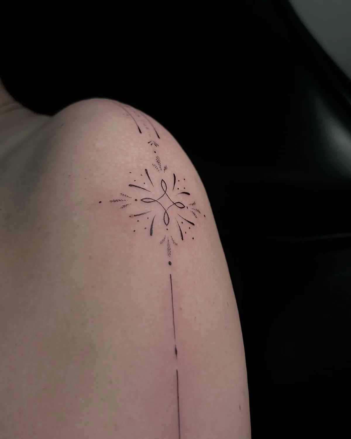 A fine-line mandala with a flower at its centre, on an upper arm.